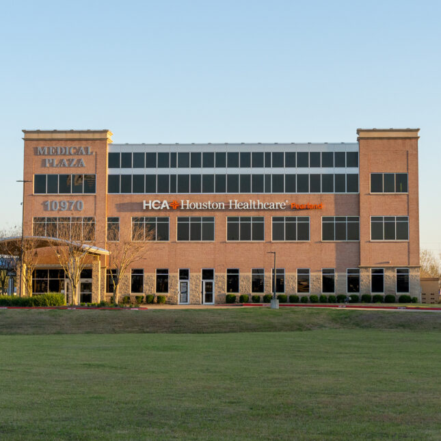 A three to four-story brick building adorned with the sign "HCA Houston Healthcare," standing in front of a grassy area — hospitals coverage from STAT