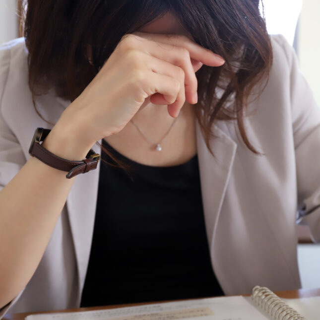 A person with short hair in a blazer supports their head while looking at a notebook — coverage from STAT