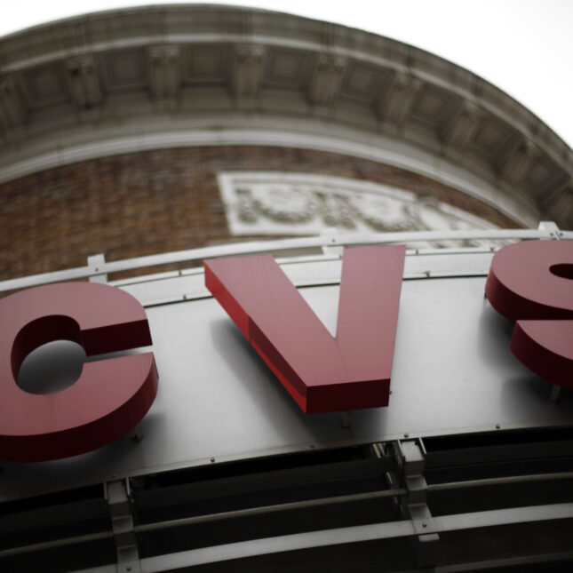 A CVS sign from below on a silver facade of a brick wall building — politics coverage from STAT