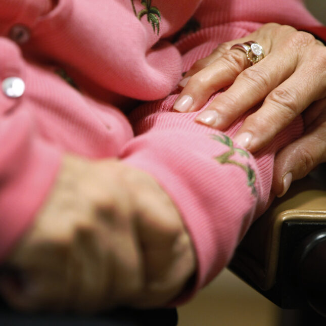 Caregiving: A close up photograph of a caregivers hand on the arms of an older loved one