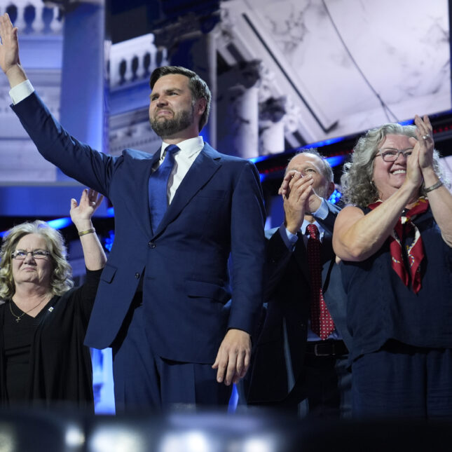 Republican vice presidential candidate Sen. JD Vance raises his right arm on stage, surrounded by family members — politics coverage from STAT