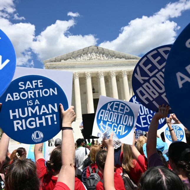 Protesters raise blue signs with white text that read "KEEP ABORTION LEGAL" or "SAFE ABORTION IS A HUMAN RIGHT!" outside the Supreme Court — first opinion coverage from STAT