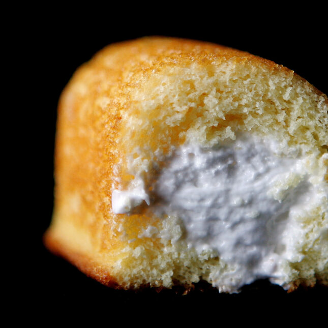 Close up photograph of part of a Hostess Twinkie golden sponge cake with its creamy filling exposed