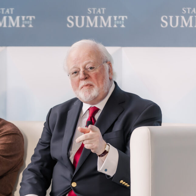 President of the American Association for the Treatment of Opioid Dependence, Mark Parrino gestures while sharing a white coach with two fellow panelists at a summit